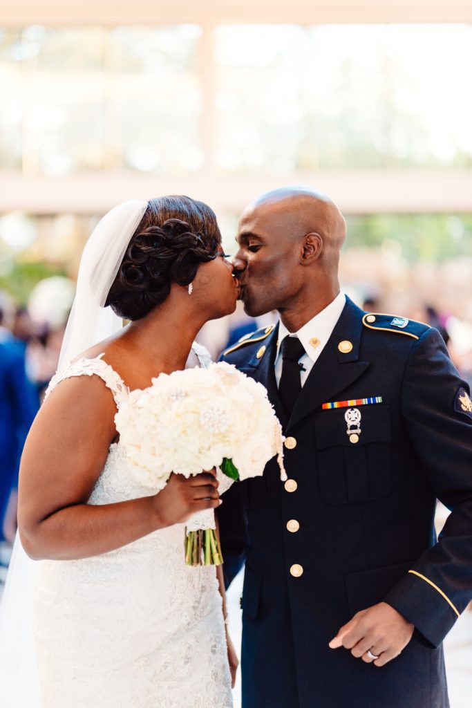 Ivoirian groom and Congolese bride kissing as they leave their wedding ceremony